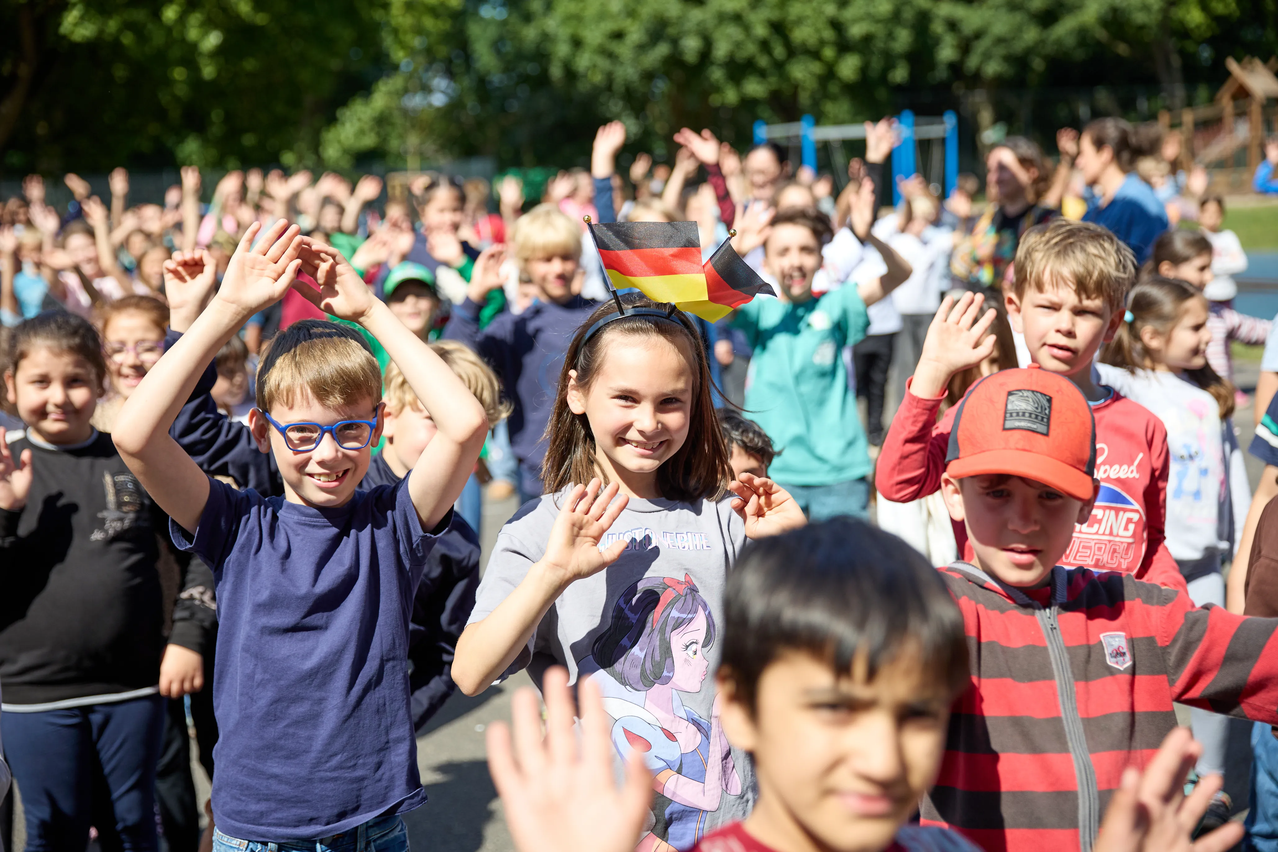 Große Gruppe Kinder tanzt gemeinsam auf dem sonnigen Schulhof