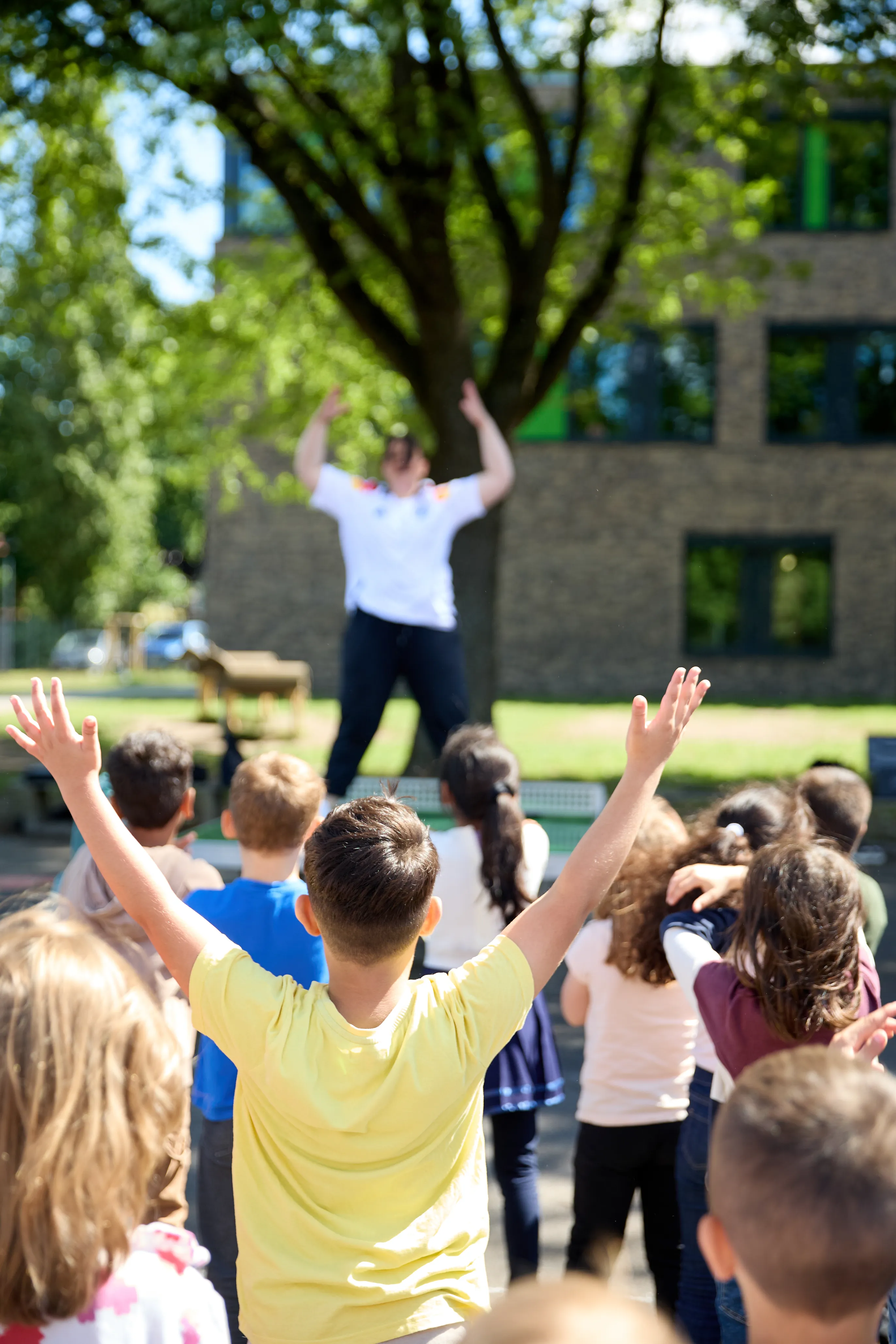 Kinder mit erhobenen Armen bei einer bewegten Aktion im Freien